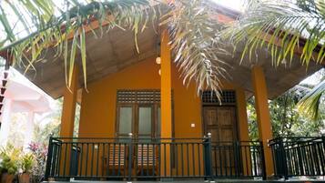 A yellow building with a covered porch, a wooden door, and a small window.
