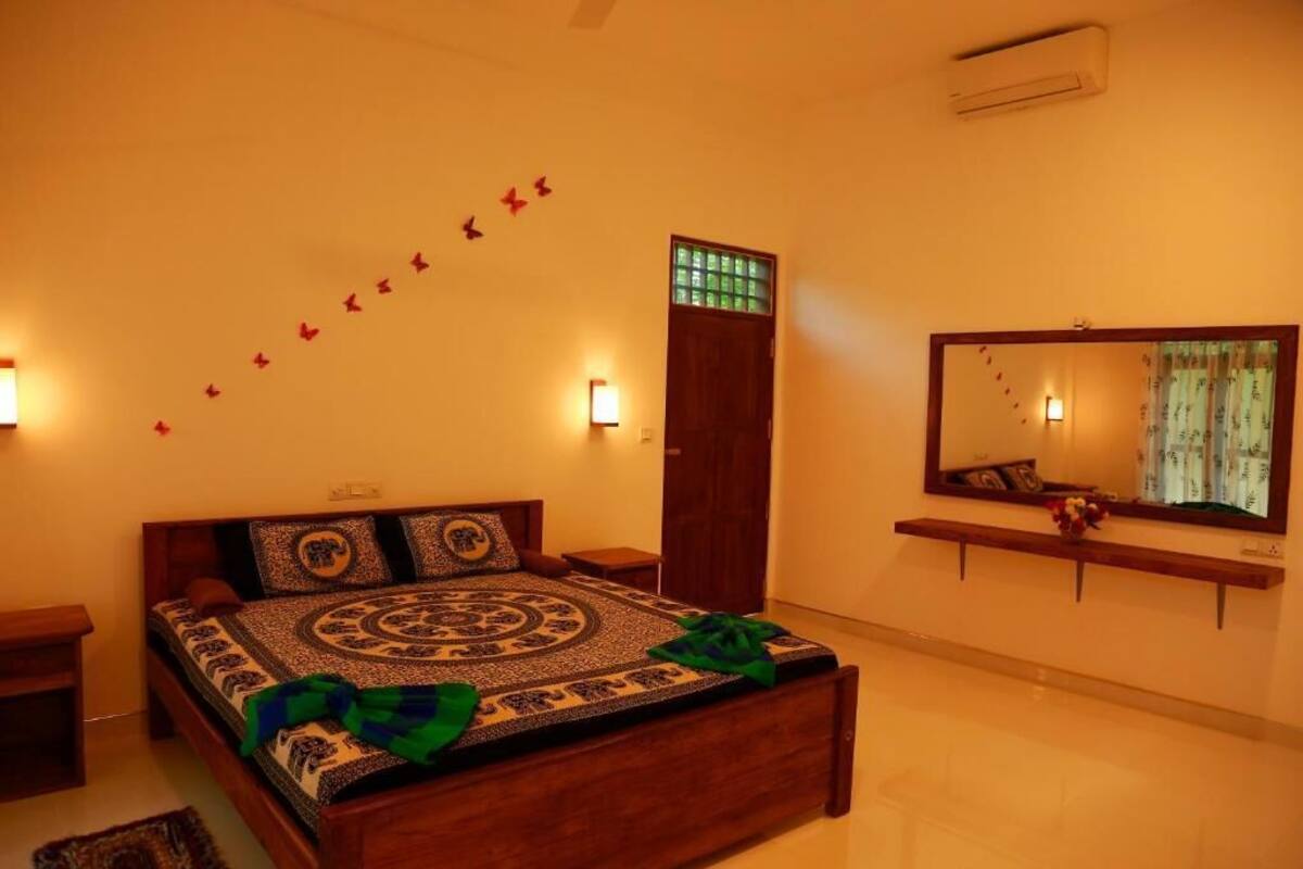 A bedroom with a bed, bedside tables, a mirror, and wall-mounted lights.