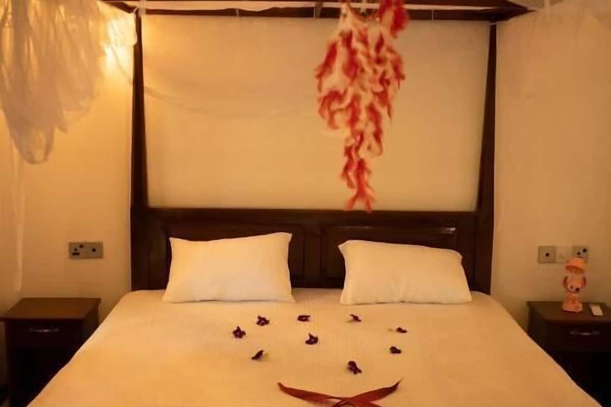 A bed with white bedding, a wooden headboard, and a decorative hanging.