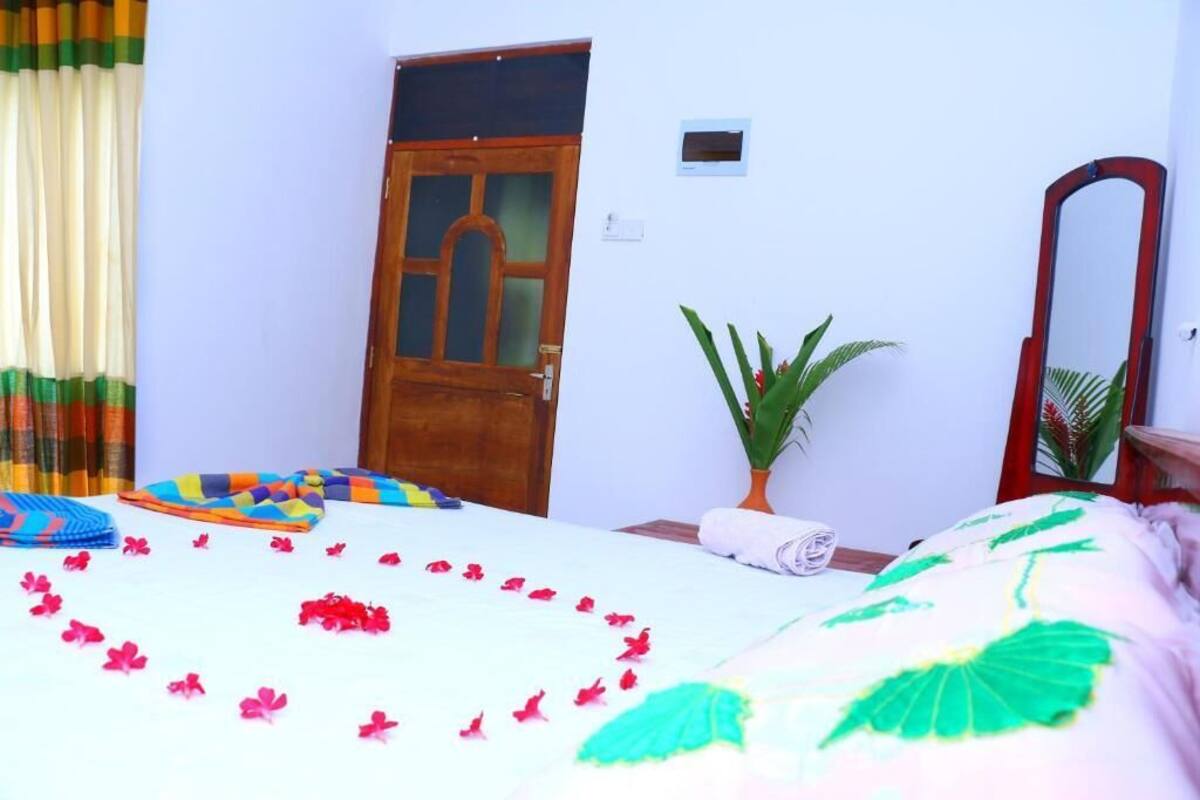 A room with a bed, a wooden door, a potted plant, and a mirror.