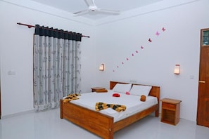 Une chambre avec un lit en bois, des rideaux blancs, un ventilateur de plafond et des autocollants décoratifs représentant des papillons sur les murs.