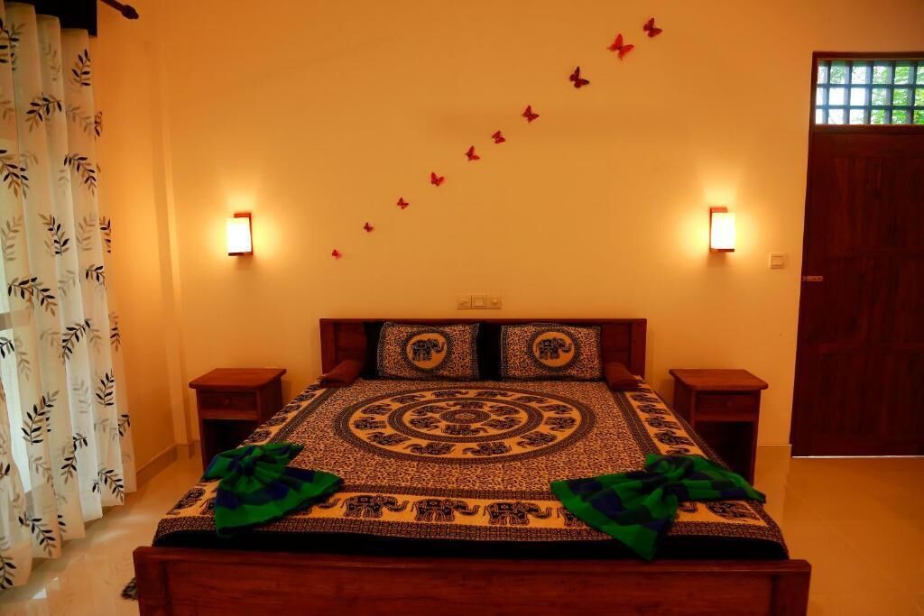 Una habitación con una cama, dos mesitas de noche, una lámpara de pared, una puerta y una ventana.