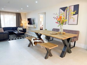 Ein modernes Wohnzimmer mit einem Holzespeise Tisch, einer Couch, einer Bank und einem Fernseher.