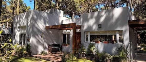 Une maison moderne dotée d’un patio, entourée d’arbres.