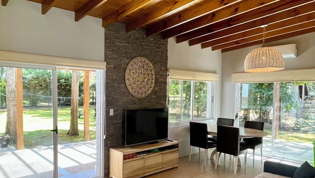 A spacious living room with a large TV, a sofa, and a dining area with chairs.