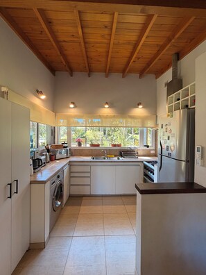 A modern kitchen with wooden beams, a built-in washing machine, and a stainless steel refrigerator.