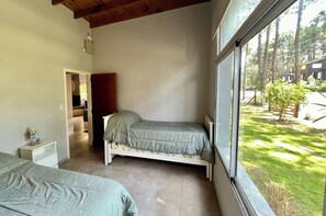 A bedroom with a bed, a nightstand, a wardrobe, and a window with a view of a garden.