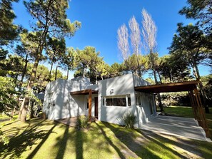A modern house with a covered patio, surrounded by trees.