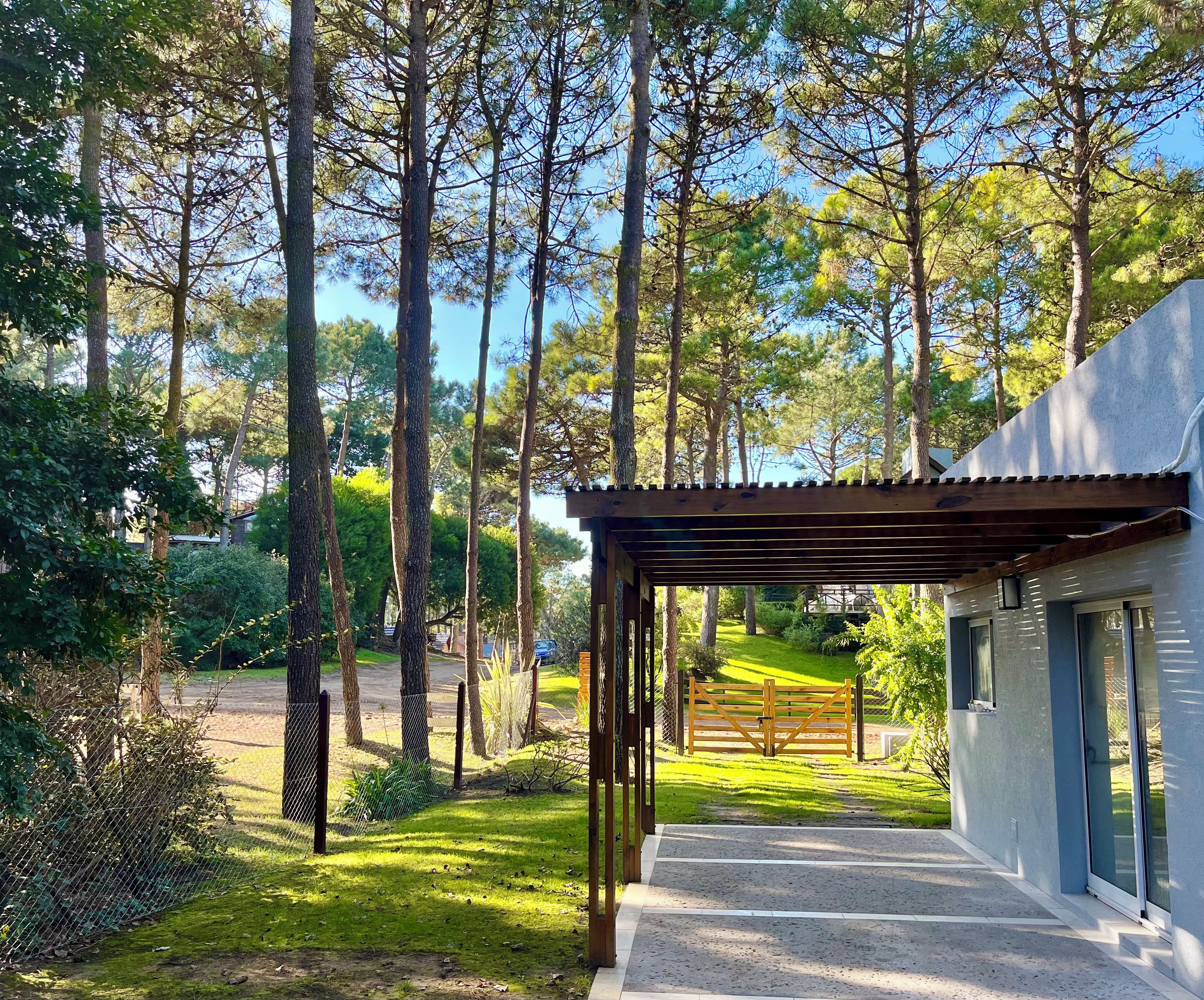 Un espacio al aire libre cubierto que conduce a un edificio moderno, con vistas a un paisaje boscoso.
