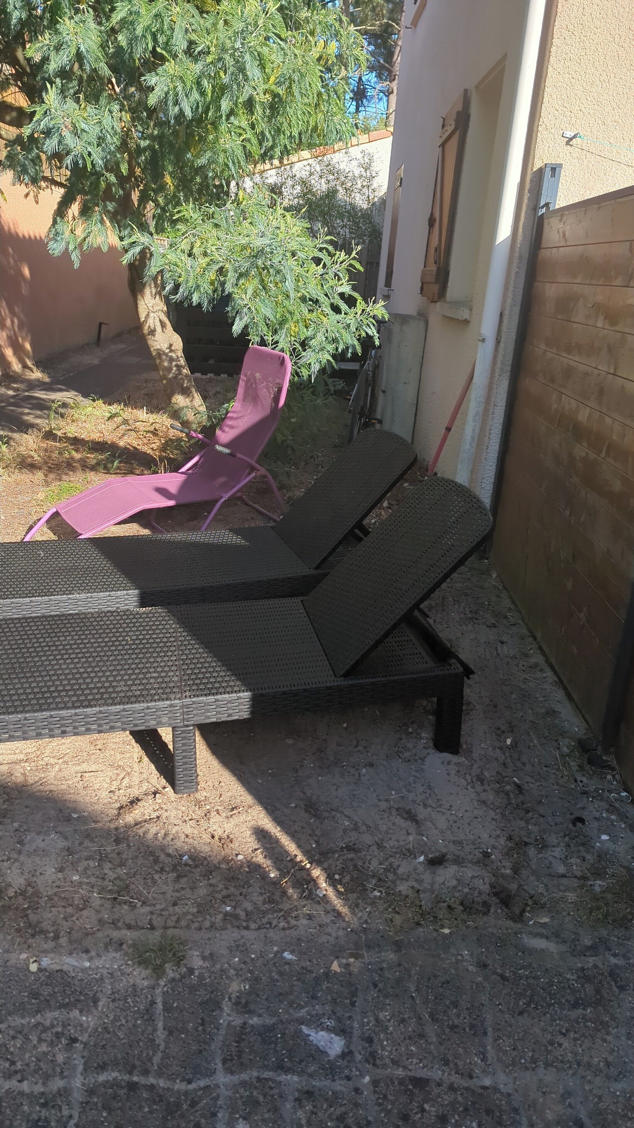 Un espace patio aménagé avec une table en métal et deux fauteuils de relaxation.