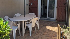 Un patio con mesa y sillas, una puerta y una verja.