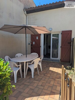 Eine Terrasse mit Tisch, Stühlen, einer Tür und einem Tor.