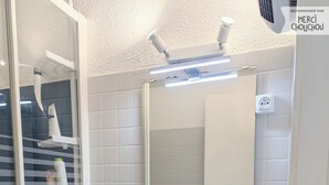 Un baño con lavamanos blanco, espejo y paredes de azulejos.