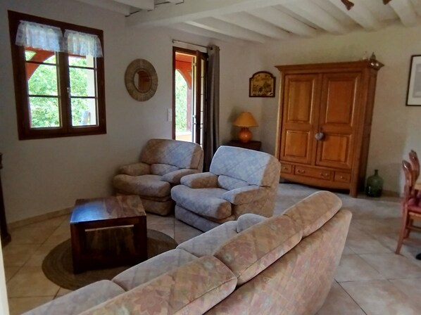 A living room with a sofa, armchairs, a coffee table, a wooden cabinet, and a lamp. - Gîte Candéjac (Daglan)