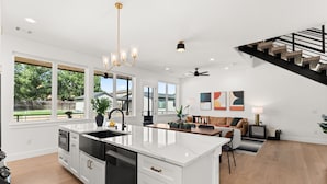 A spacious kitchen with a large island, a dining area with a sofa, and a staircase.