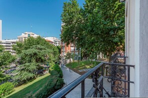 A balcony with a metal railing overlooking a courtyard with trees and a building in the background. - Central 2BD Apt Facing Torre Madrid Duque de Osuna (Madrid)