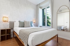 Ein Schlafzimmer mit Bett, Nachttischlampen, einem Nachttisch, einem Fenster mit Blick und einem Spiegel.