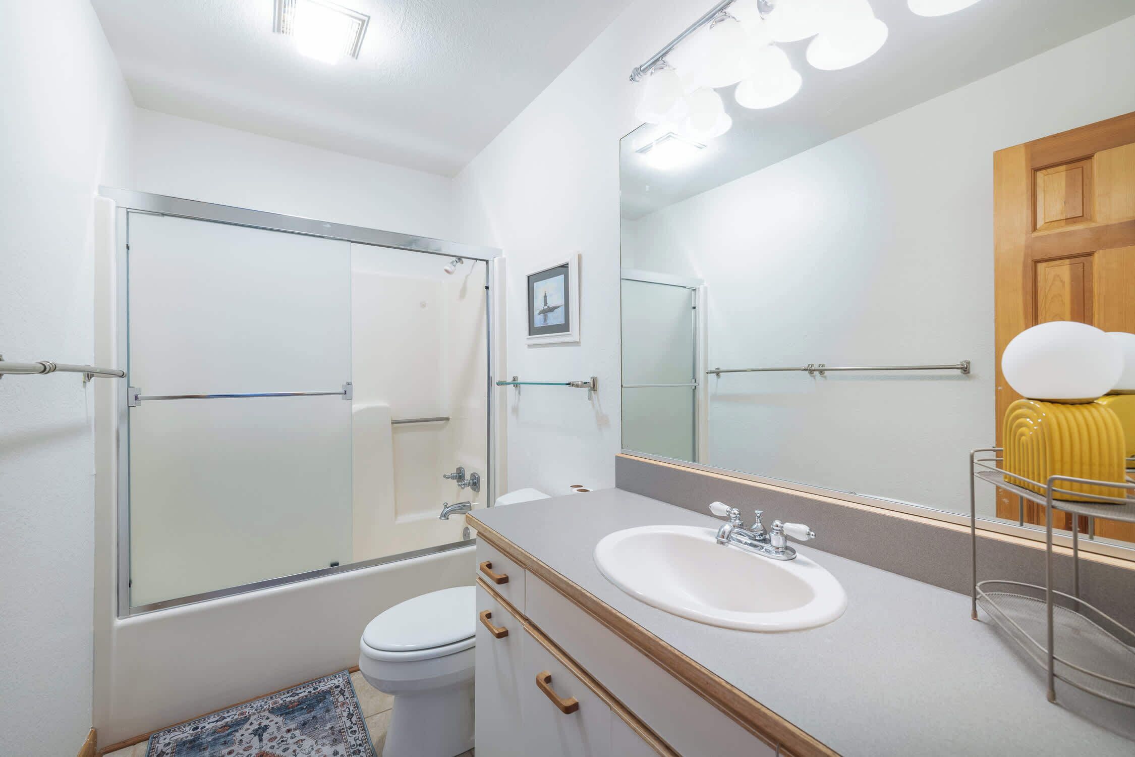 A modern bathroom with a glass shower enclosure, a white sink, and a wooden vanity.