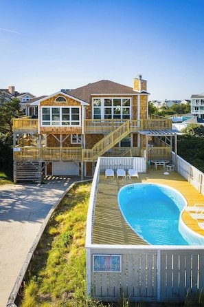 Ein zweistöckiges Haus mit Pool, Sitzgelegenheiten im Freien und einer Terrasse.
