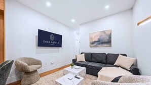 A modern living room with a sofa, two side chairs, a coffee table, and a painting on the wall. - The Gerrard | Group Basement CN Tower Transit Base (Toronto)