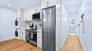 Una cocina moderna con armarios blancos, electrodomésticos de acero inoxidable y piso de madera.