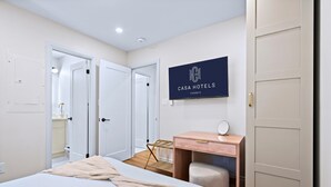 Una habitación de hotel con cama, escritorio, silla, espejo y armario.