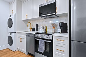 A modern kitchen with white cabinets, stainless steel appliances, and wooden handles.