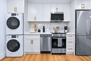 A modern kitchen with a stainless steel refrigerator, oven, dishwasher, and washing machine.