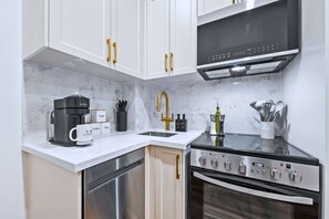 Une cuisine moderne avec des meubles blancs, une machine à café, un évier et une cuisinière.
