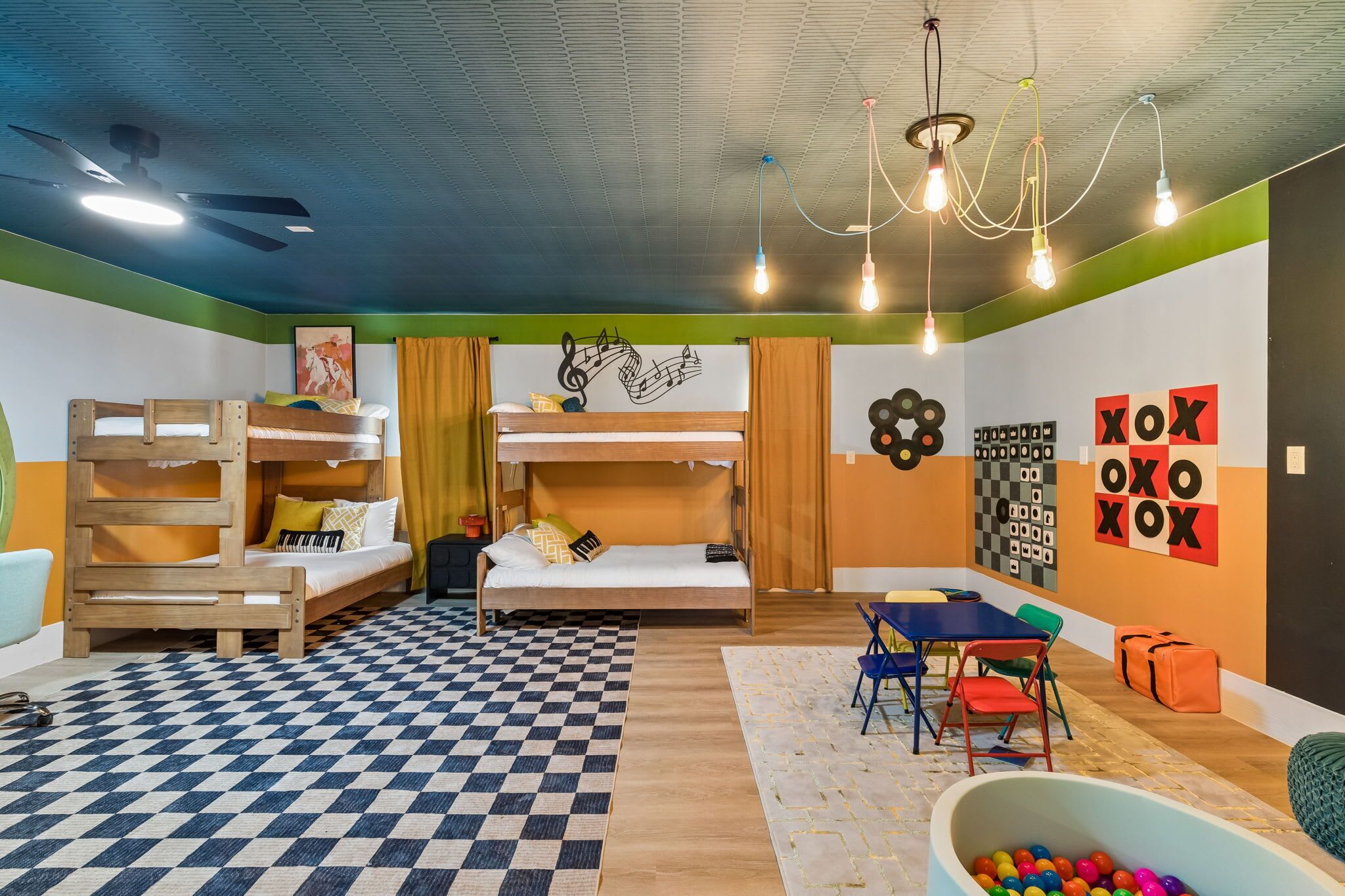 Habitación con literas, un escritorio, una silla, una mesa y una zona de juegos con pelotas.