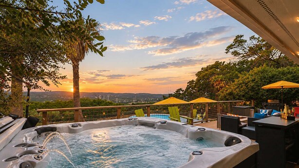 A hot tub with a sunset view, outdoor seating, and umbrellas. - The Lakeside Soundtrack | Pool, Hot Tub, Games (Spicewood)