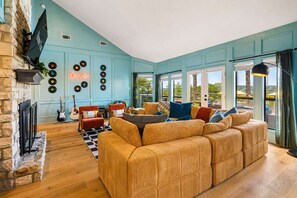 A living room with a large sofa, two armchairs, a fireplace, a guitar, and a wall with vinyl records. - The Lakeside Soundtrack | Pool, Hot Tub, Games (Spicewood)