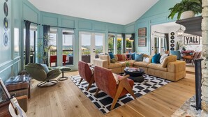 A spacious living room with a large sofa, a coffee table, and a record player. - The Lakeside Soundtrack | Pool, Hot Tub, Games (Spicewood)