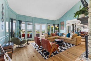 A spacious living room with a large sofa, a coffee table, and a record player. - The Lakeside Soundtrack | Pool, Hot Tub, Games (Spicewood)