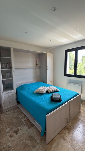 Une chambre à coucher avec un lit, une armoire, une fenêtre et un radiateur.