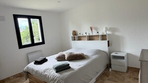 A bedroom with a bed, a nightstand, a shelf with decorative items, and a window. - House with private spa and large garden - Provence Luberon (La Bastidonne)