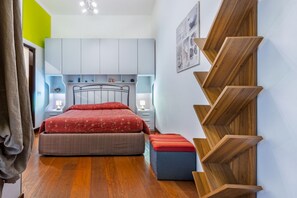 A bedroom with a bed, bedside tables, a wall-mounted wooden shelf, and a window. - GuestHost - Domus Genovesi Apartment in Casteddu (Cagliari)