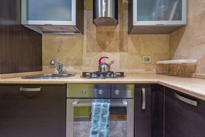 A kitchen with a gas stove, sink, and oven. - GuestHost - Domus Genovesi Apartment in Casteddu (Cagliari)