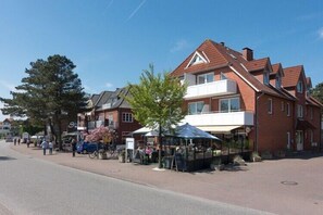 A street with buildings, a café, and a bicycle. - Ferienwohnung in St. Peter-Ording (St. Peter-Ording)