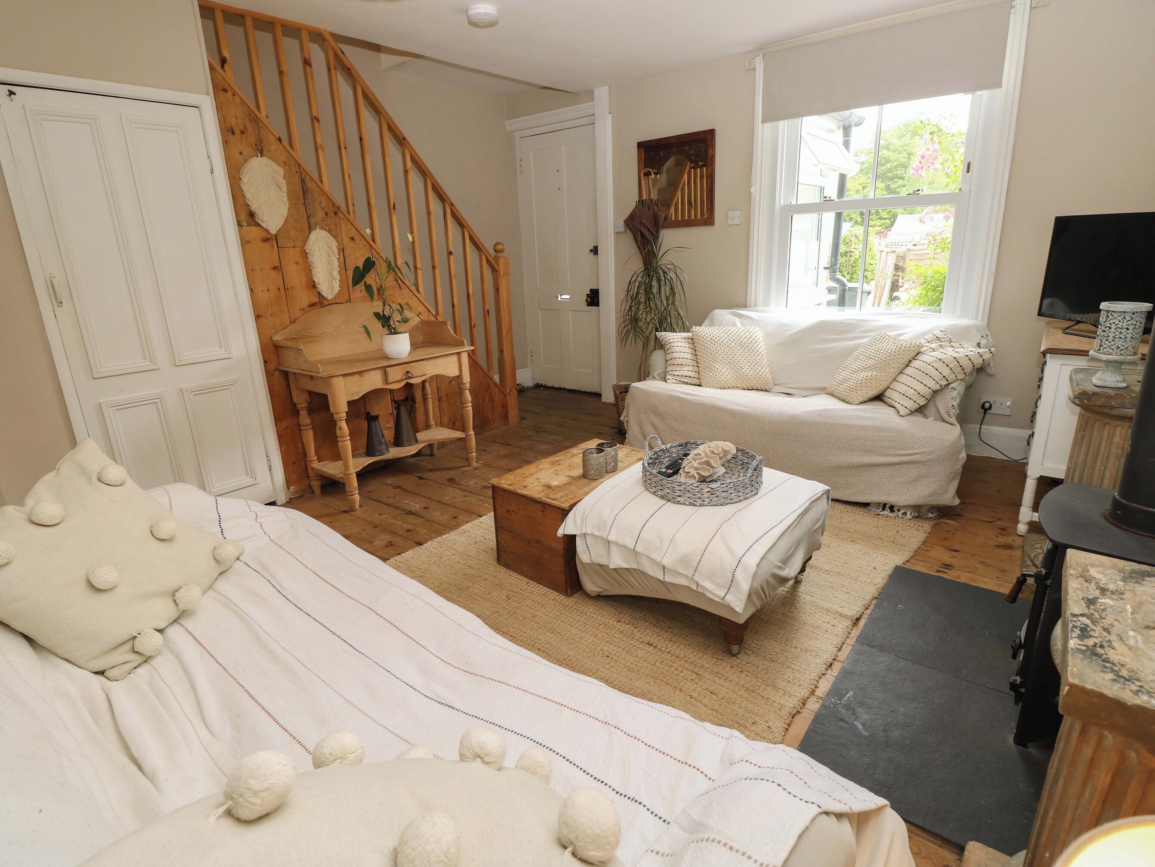 A cozy living room with a staircase, a sofa, a coffee table, and a television.