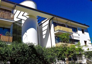 Ein modernes Gebäude mit Balkonen, großen Fenstern und einer zylinderförmigen Struktur.