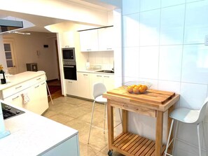 Eine moderne Küche mit weißen Schränken, einem Holztisch und einem weißen Stuhl.
