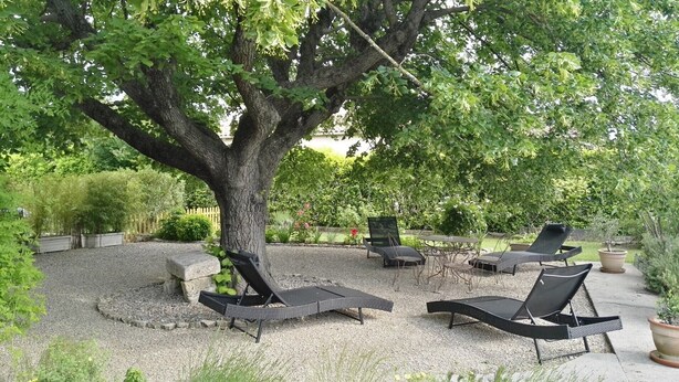 A tree-lined outdoor seating area with lounge chairs and a table. - The Bicentennial Linden Cottage (Pernes-les-Fontaines)