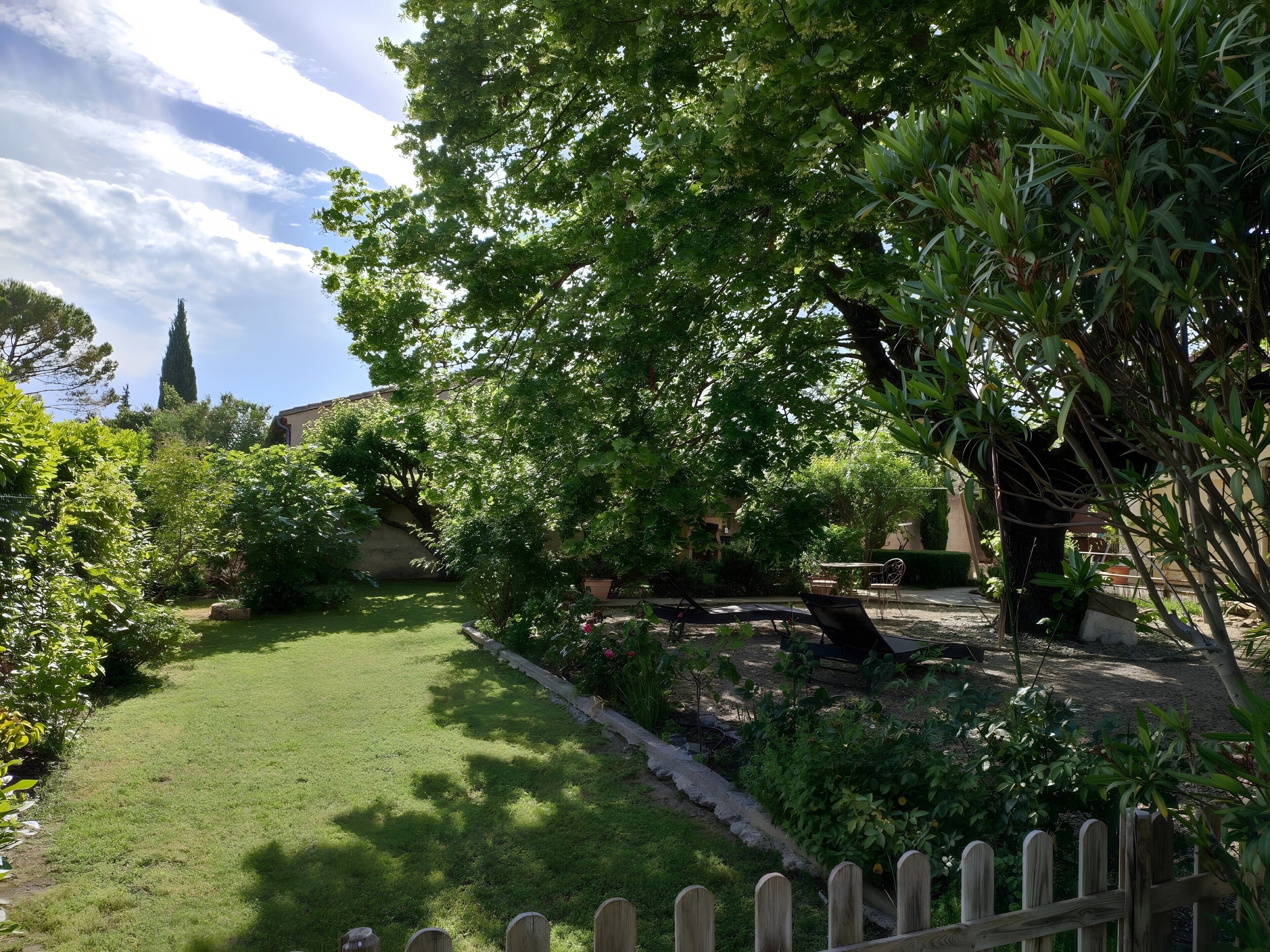 A garden with a lawn, a wooden fence, and various plants.