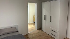 Un dormitorio con cama, armario y puerta que da a otra habitación.