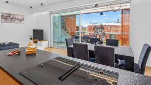 Un salon moderne avec un coin repas, de grandes fenêtres et une vue sur l’extérieur.