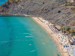A coastal beach with clear turquoise waters, a sandy shore, and a rocky cliff. - Melosa – Your Holiday Retreat in Burgau (Luz)