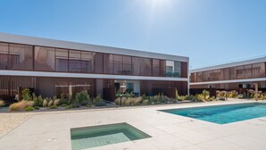 Un bâtiment moderne doté d’une piscine, d’un espace extérieur aménagé et offrant une vue sur un ciel dégagé.