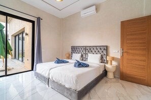 Ein Hotelzimmer mit einem großen Bett, einer Holztür, einer Schiebetür zum Außenbereich und einer wandmontierten Klimaanlage.