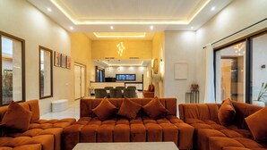 Una sala de estar moderna con un sofá modular, una mesa de centro y un televisor al fondo.